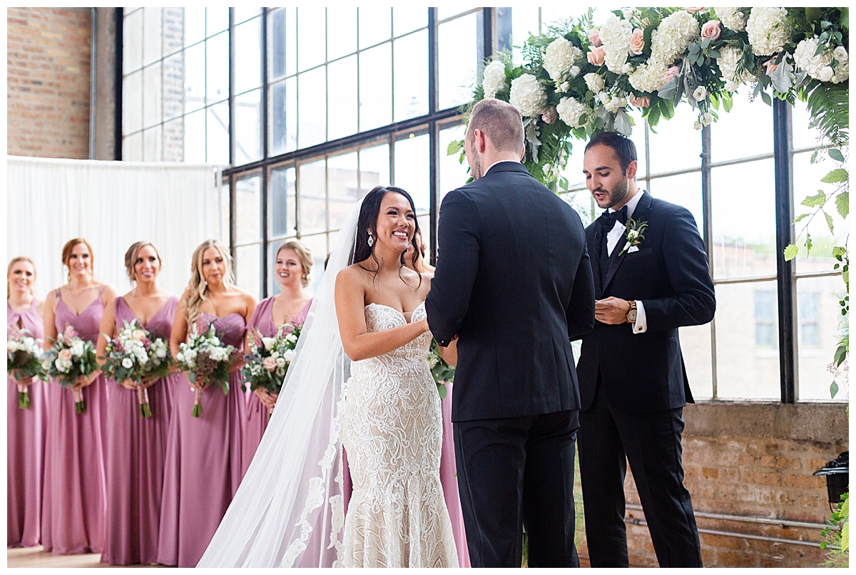 Bride and groom recite their vows while bridesmaids look on 
