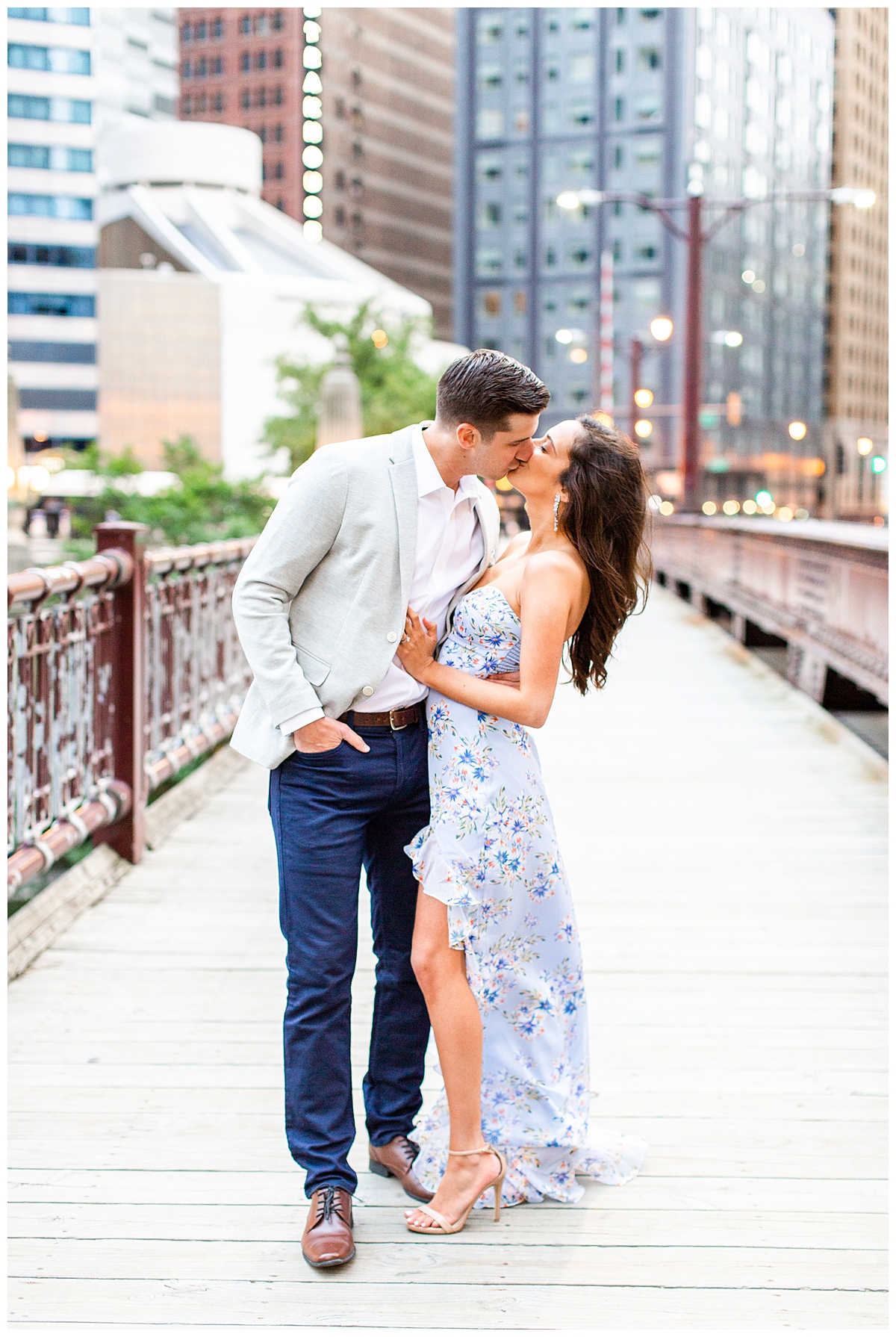 A couple kisses in their engagement photo on the red bridge near the Wrigley building in chicago. 