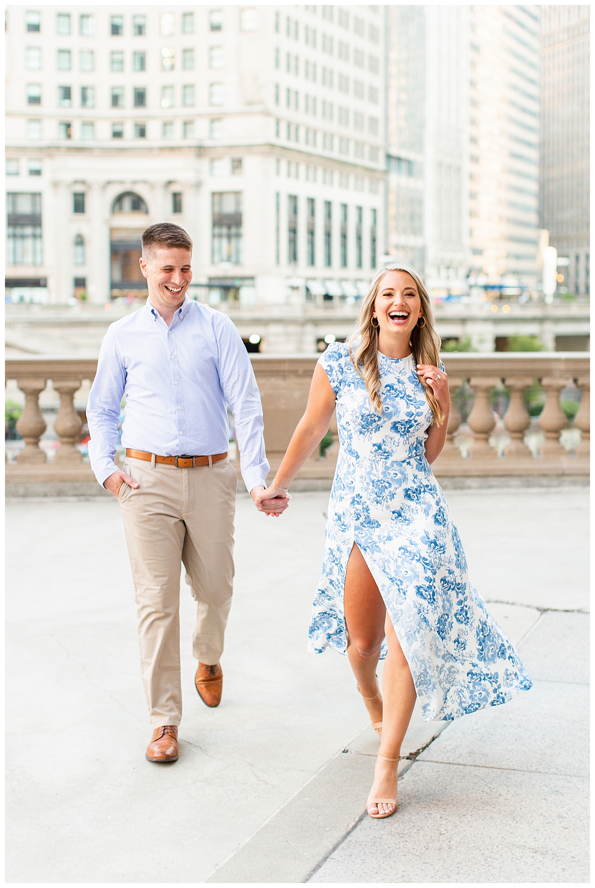 A couple takes their engagement portrait outside of the Wrigley Building in Chicago. They are dressed for summer in shades of blue and tan. 