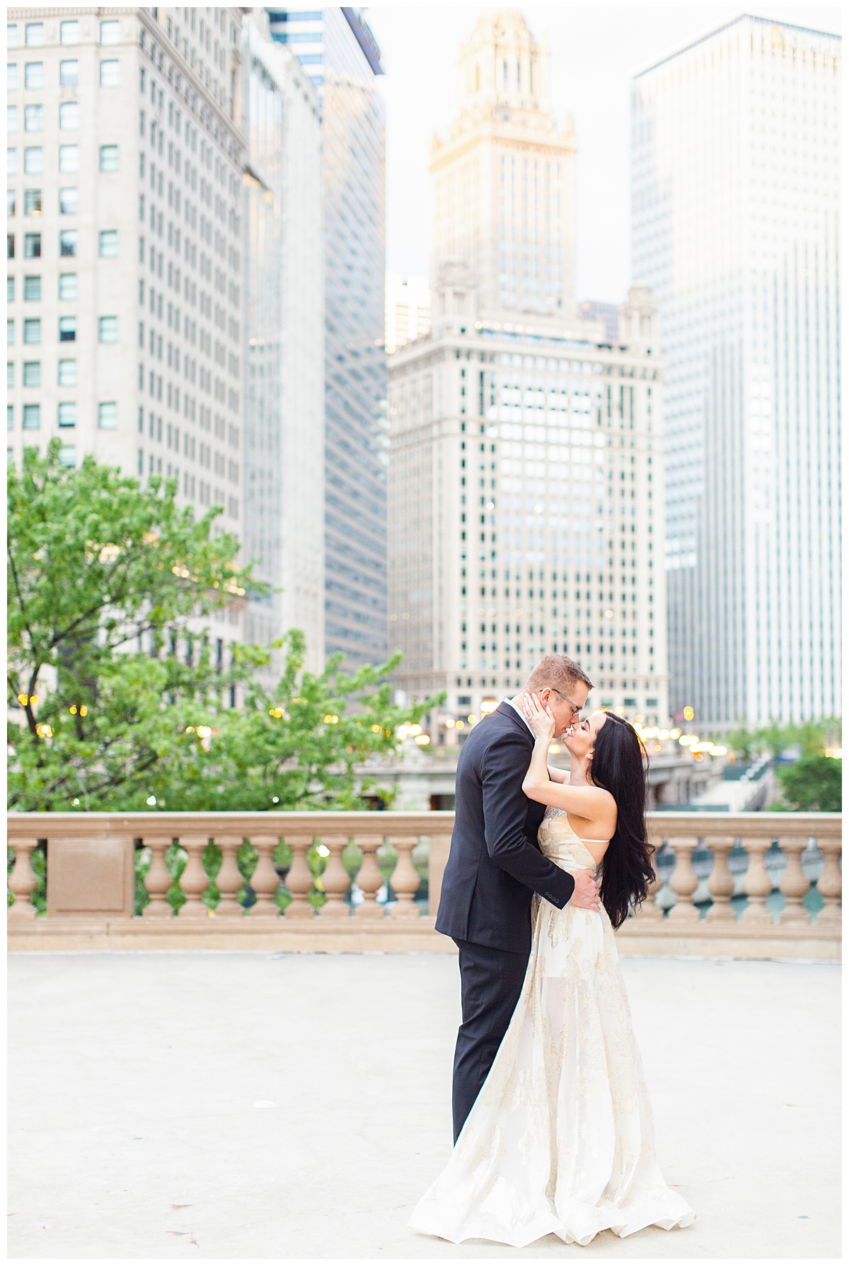 A bride and groom kiss in a wedding portrait at the Wrigley Building in Chicago. The city skyline is in the background. 