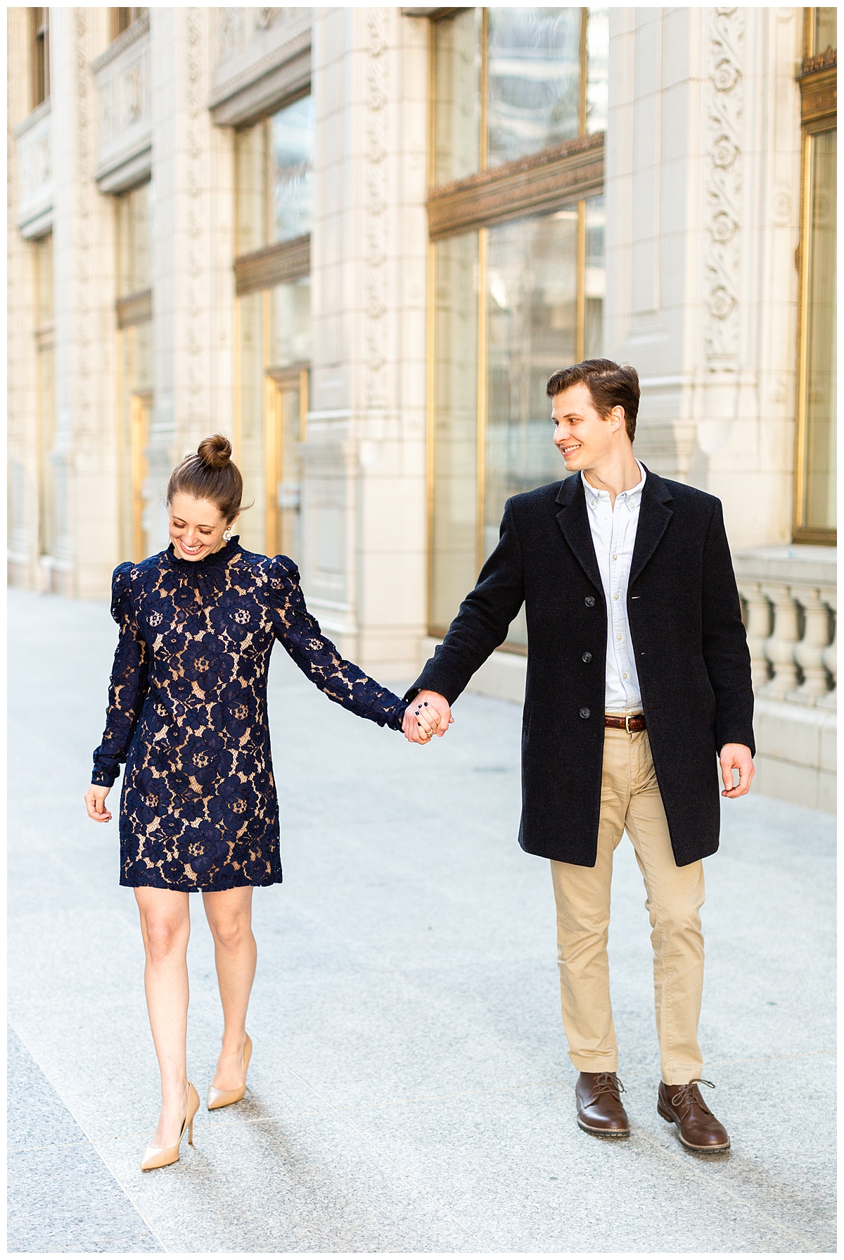 A couple take an engagement portrait at the Wrigley Building in Chicago. They are dressed very elegantly and stylishly in shades of blue and tan. 