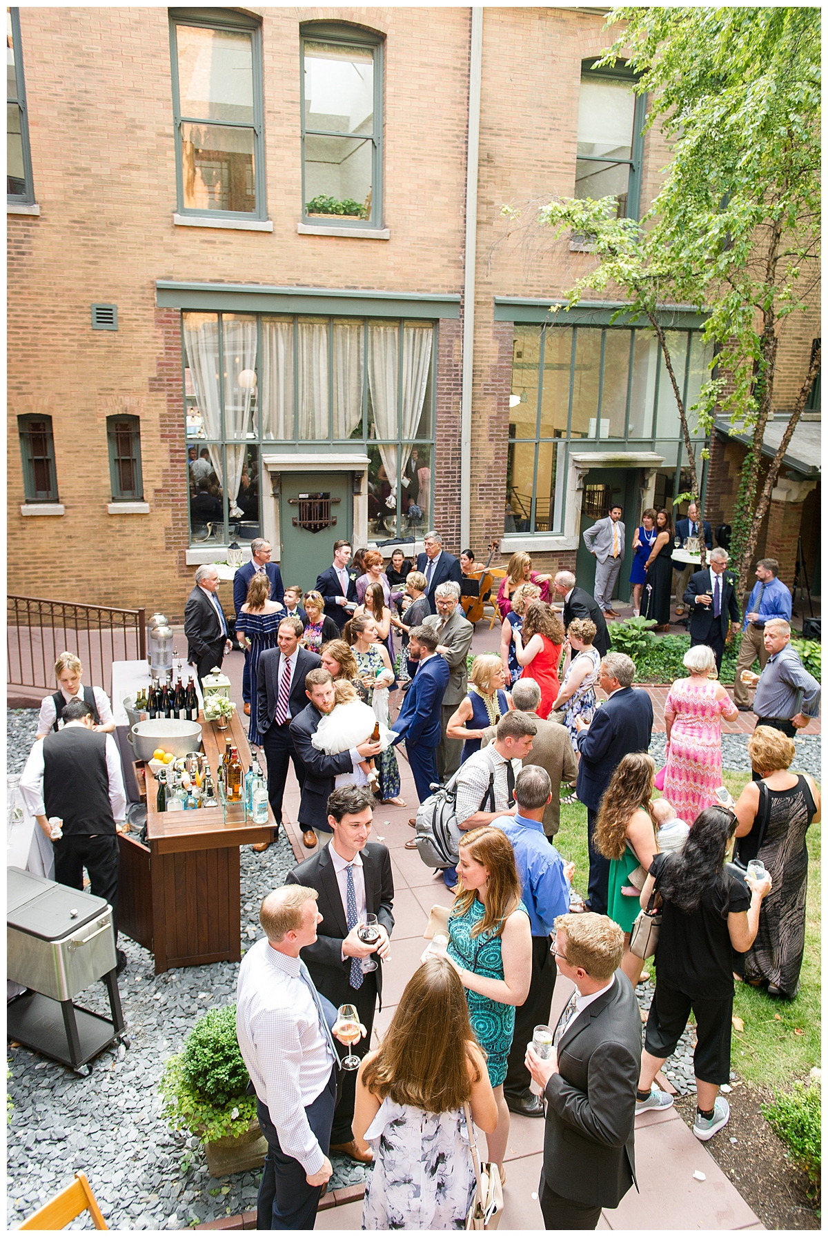 The courtyard at the Ivy Room is set up for a cocktail hour. Guests are milling about enjoying the bar. 