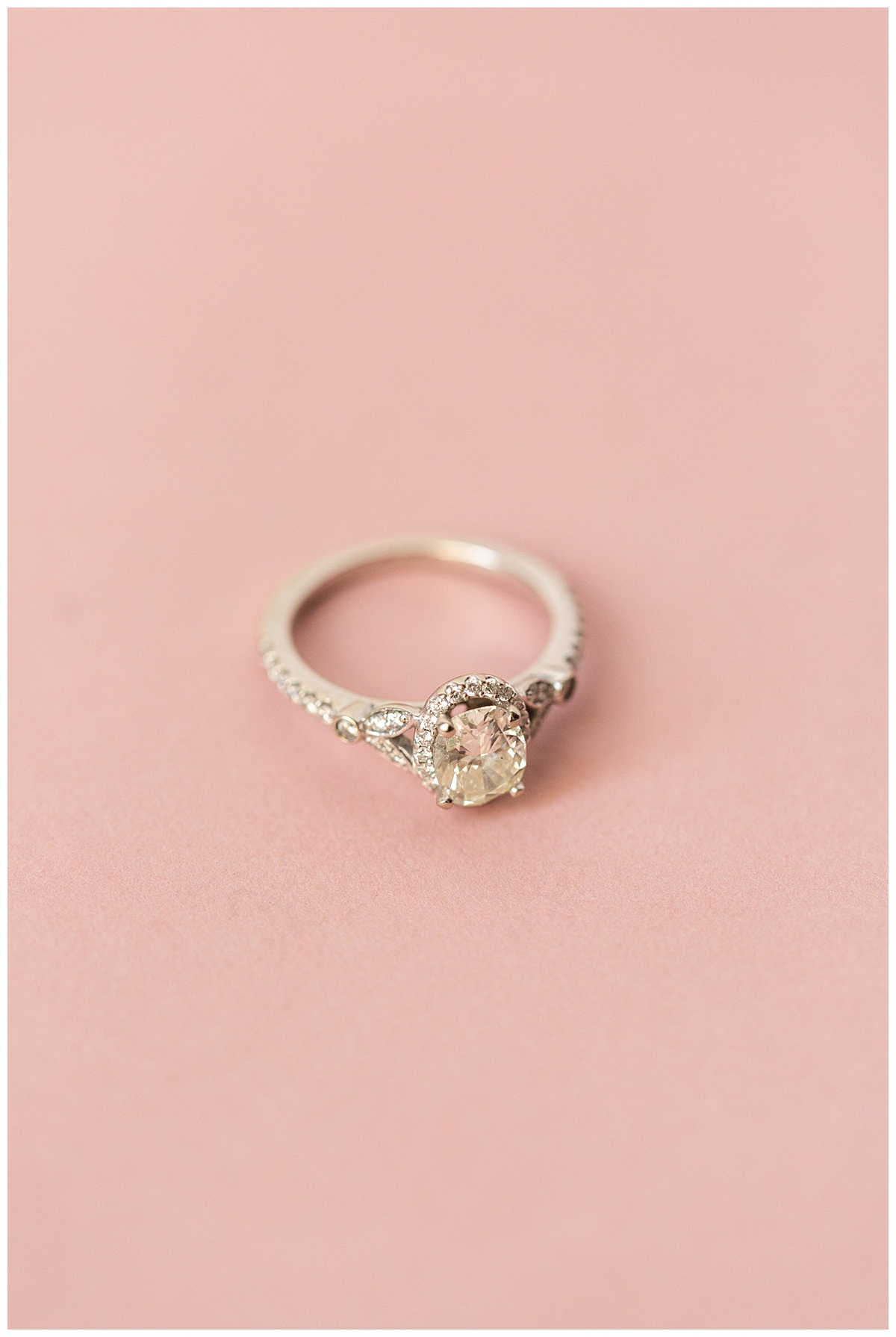 The bride's engagement ring is displayed on a pink background. 