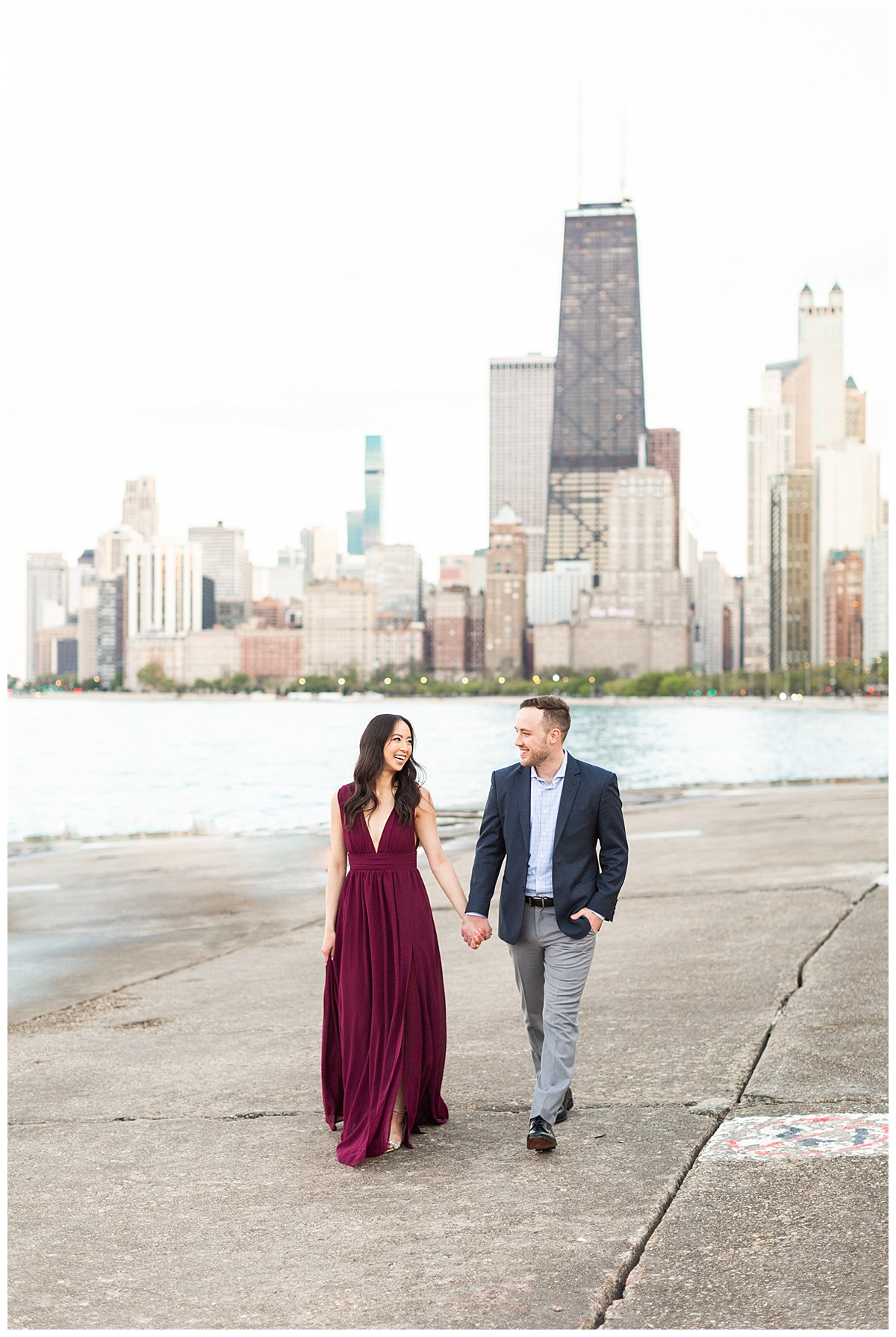 A couple poses in their engagement portrait with downtown chicago in the background