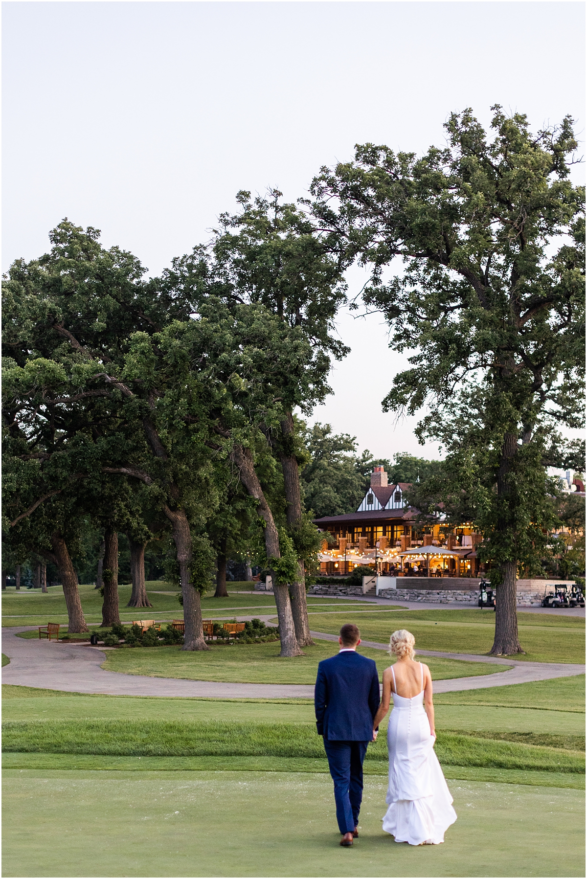 newlyweds walk together holding hands heading back towards Classic and Romantic Wedding reception at River Forest Country Club 