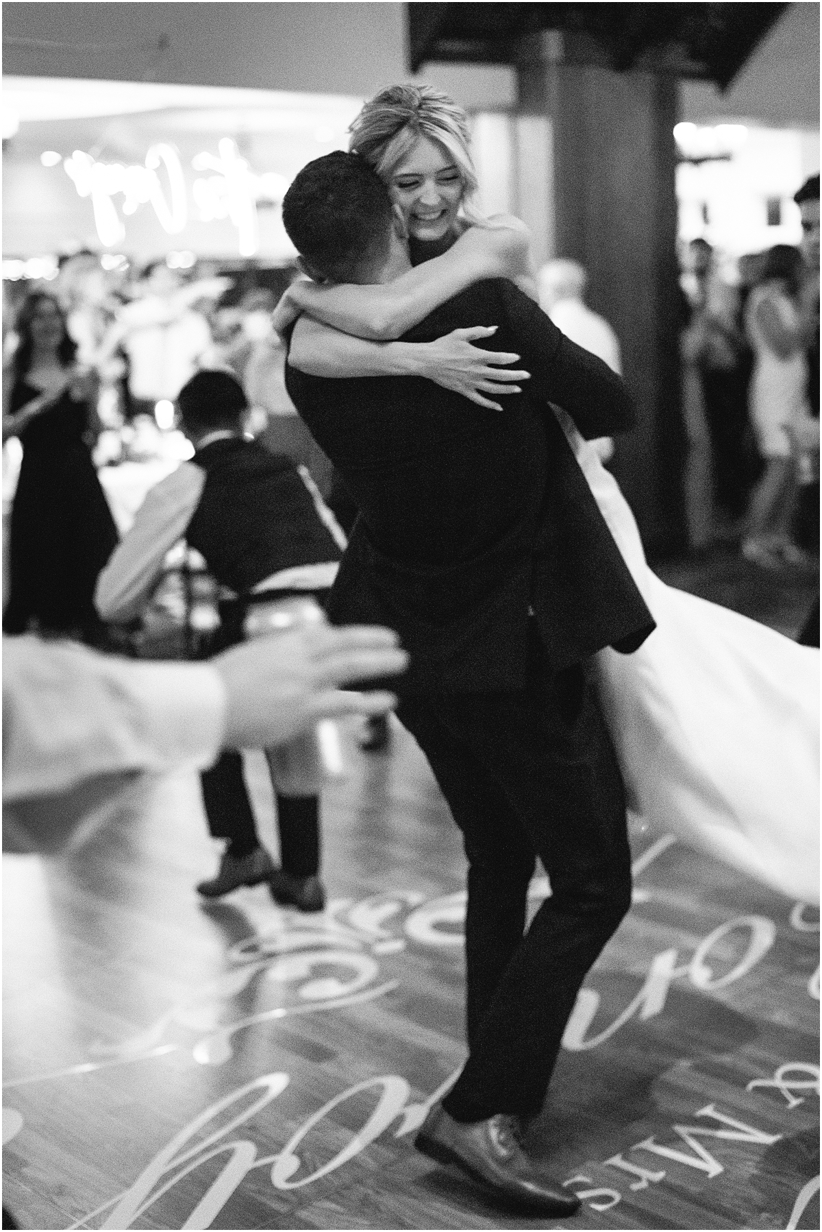 groom lifts his bride up on the dance floor