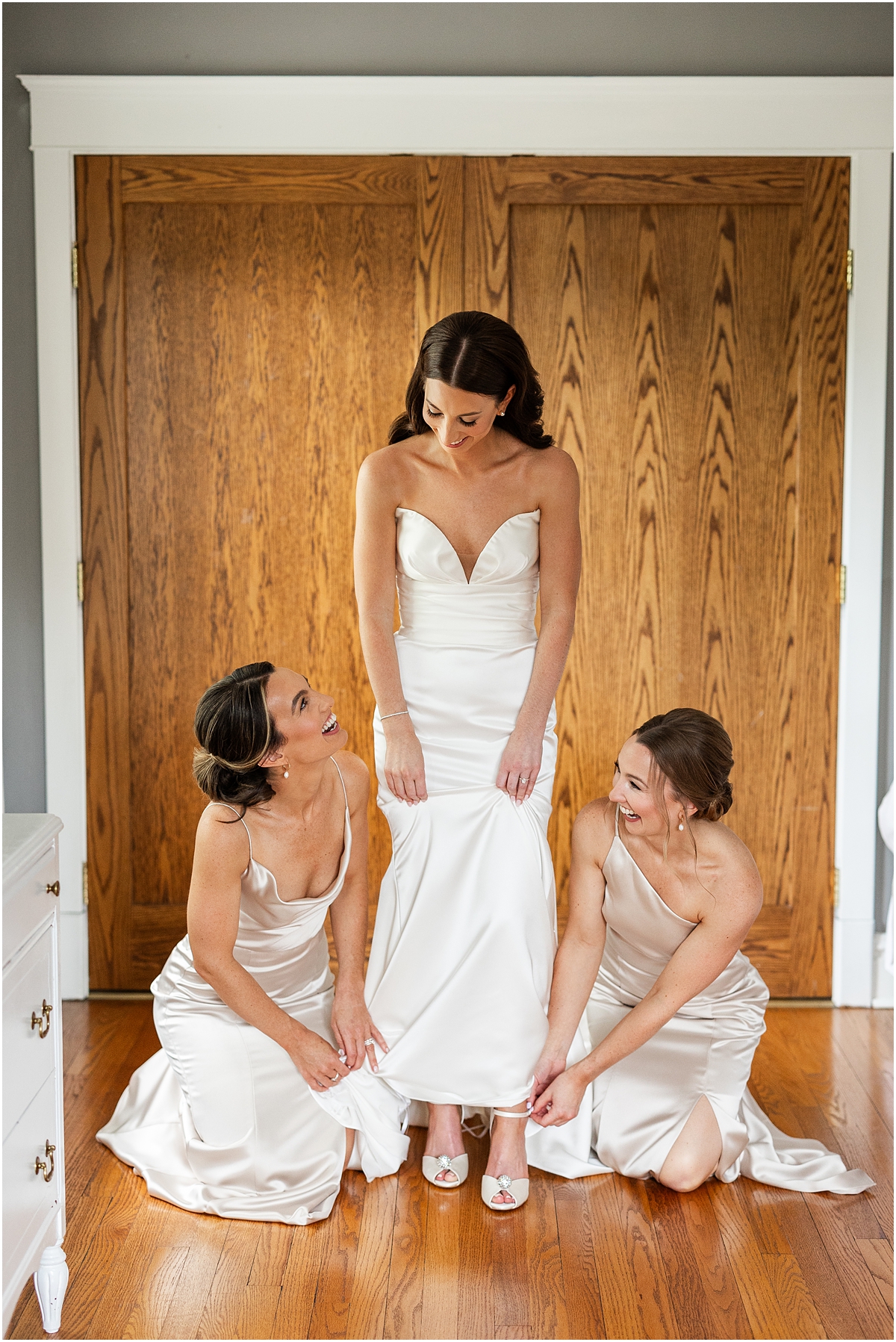 bridesmaids help bride with wedding shoes