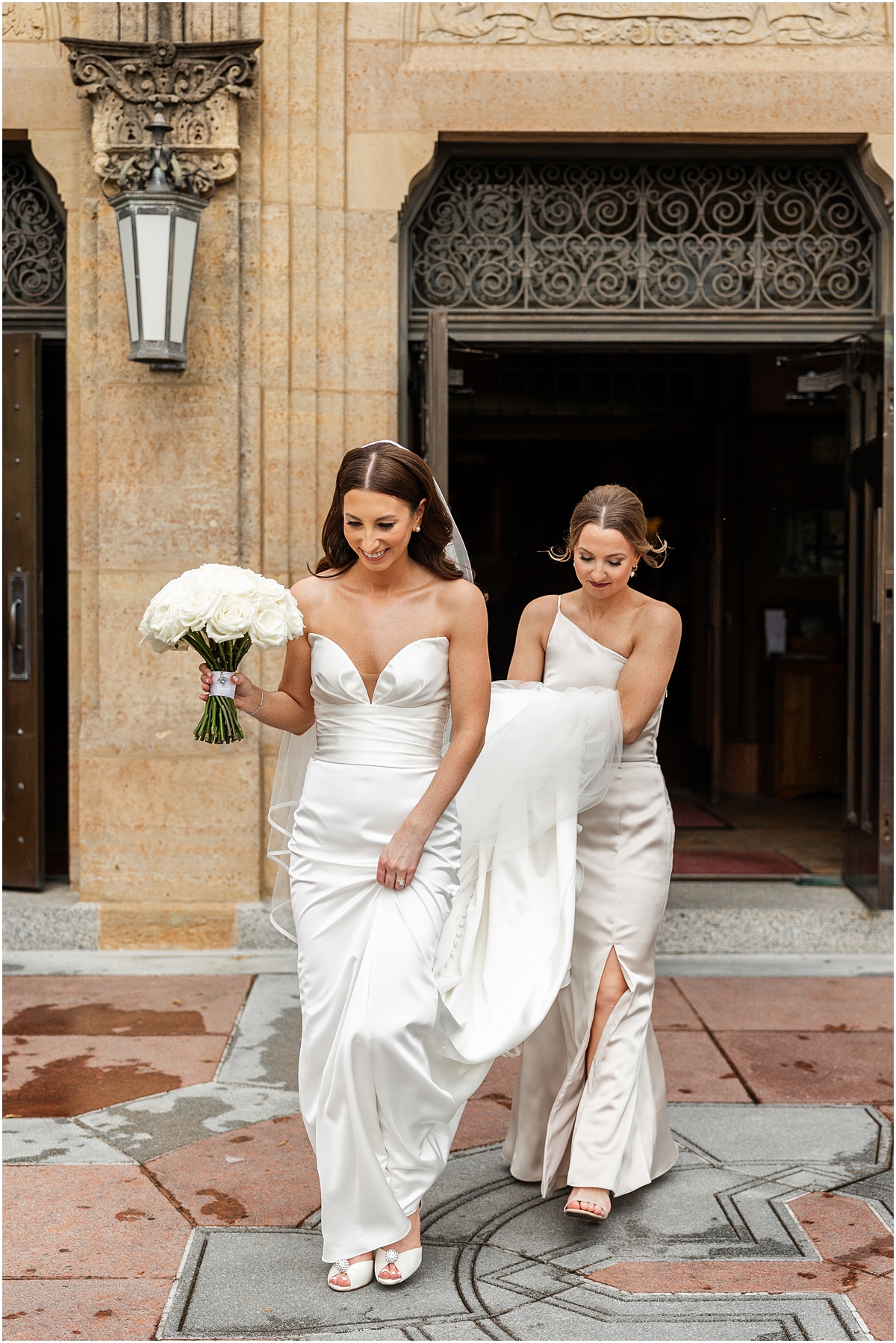 bridesmaid helps bride with dress