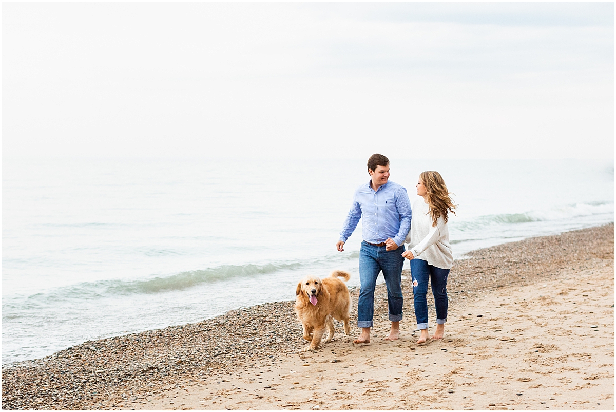 Engaged couple walk their dog on the beach of Lake Michigan 