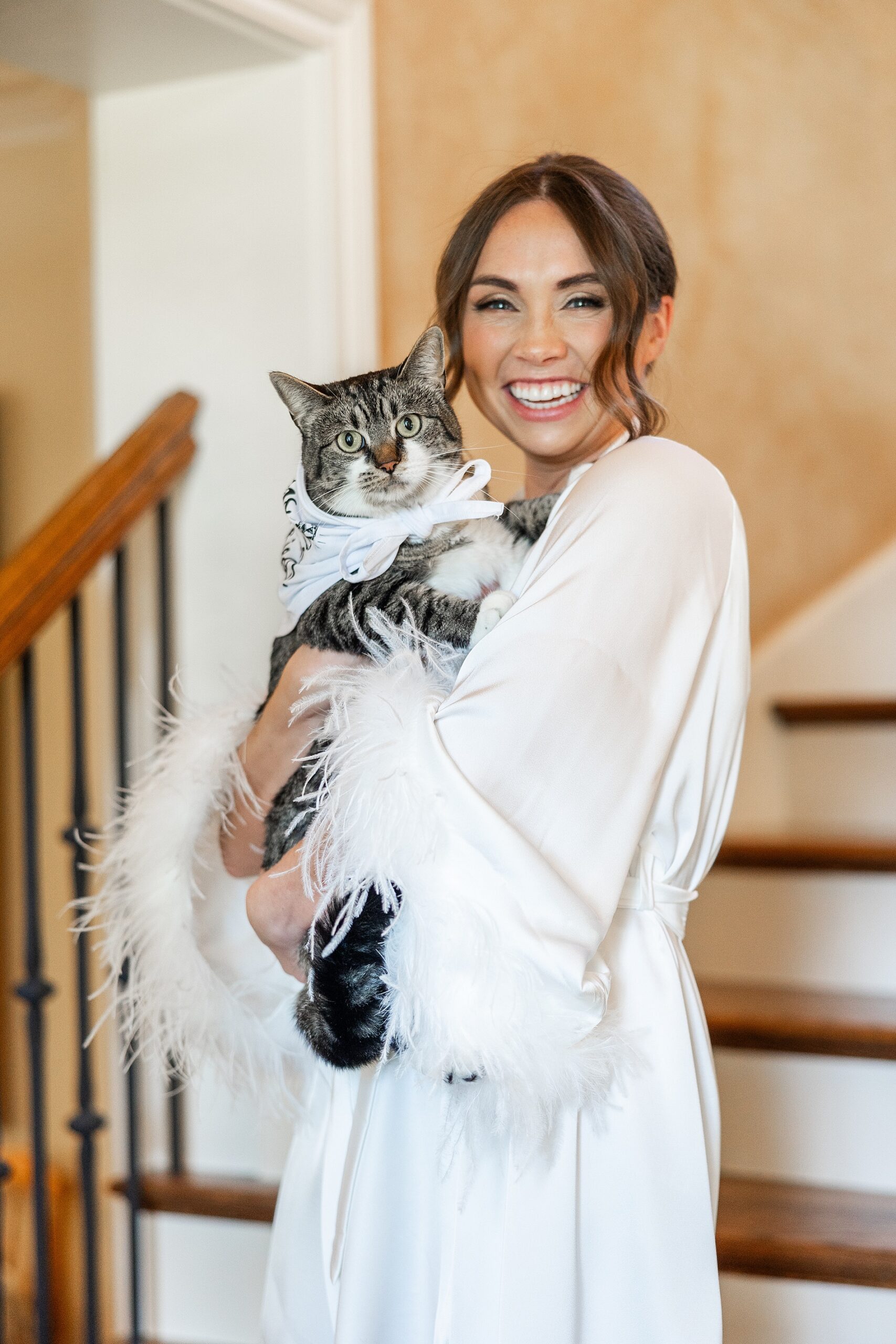bride holding cat while getting ready for wedding