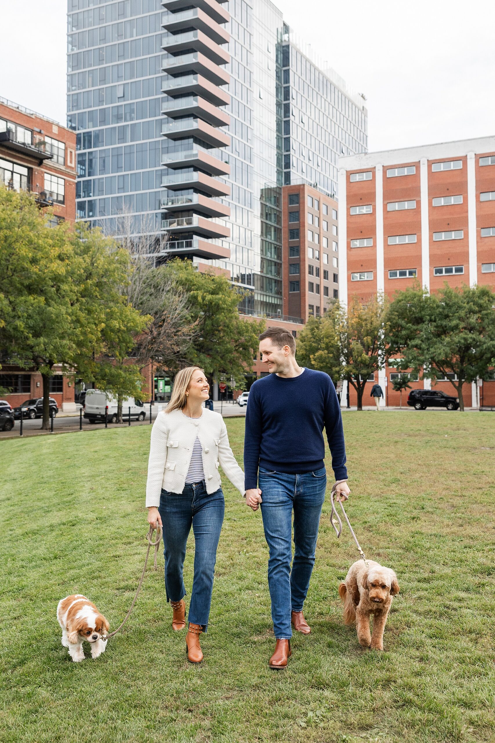 Couple walks their two dogs in West look Chicago dog park during engagement session