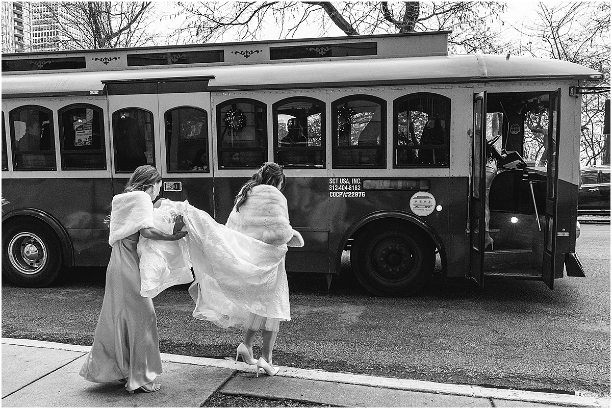 bridesmaid helping bride carry wedding dress