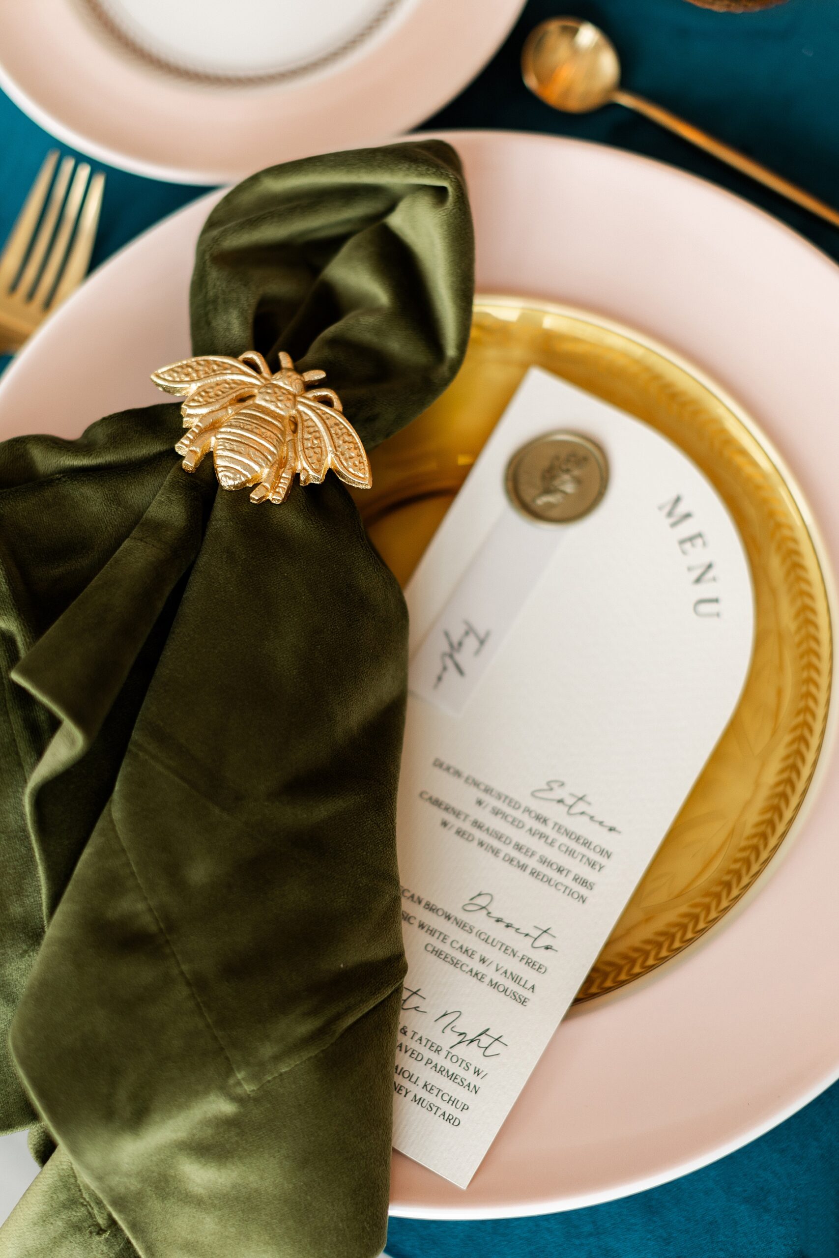 dark green napkins with golden bee napkin ring on top of custom menu with gold wax seal