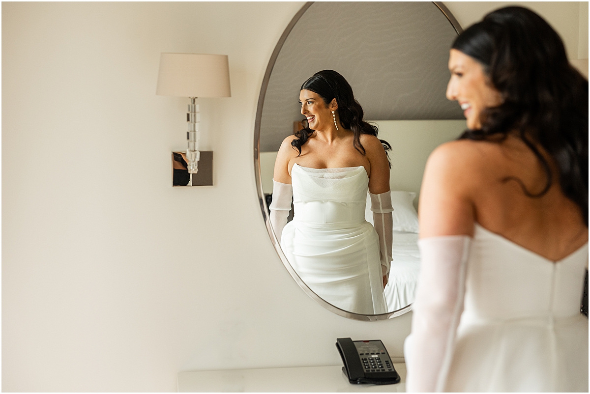 bride in wedding dress looks in mirror