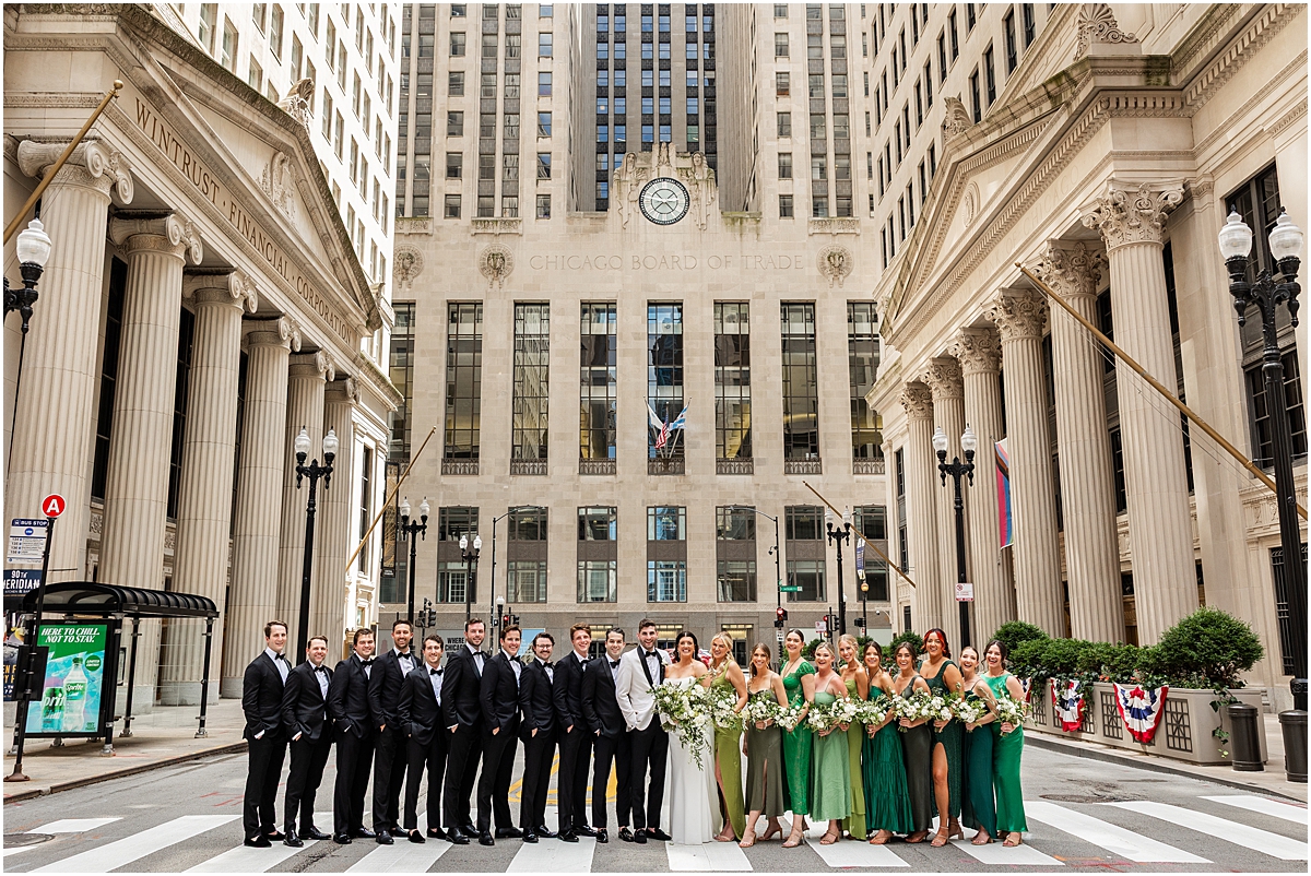 large wedding party take photos outside of the Board of Trade building in Chicago