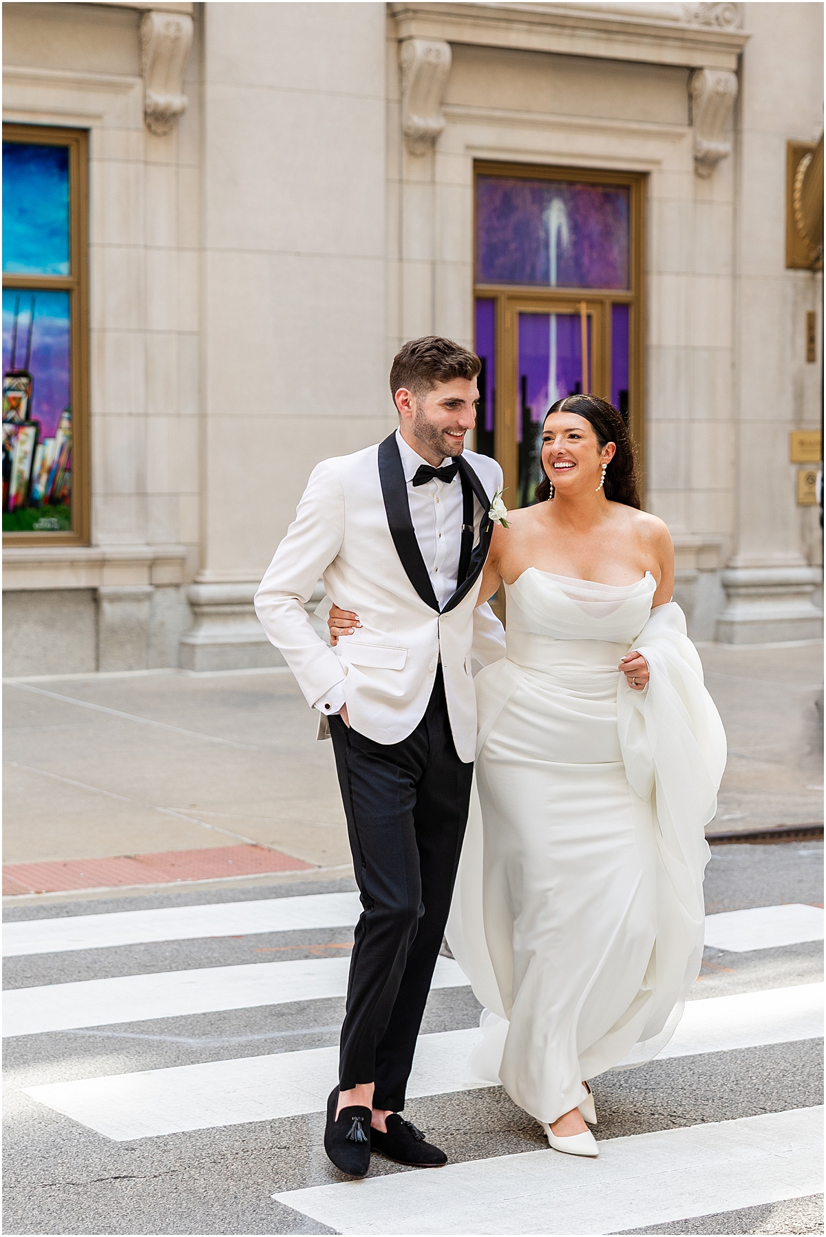bride and groom laugh as they cross street together