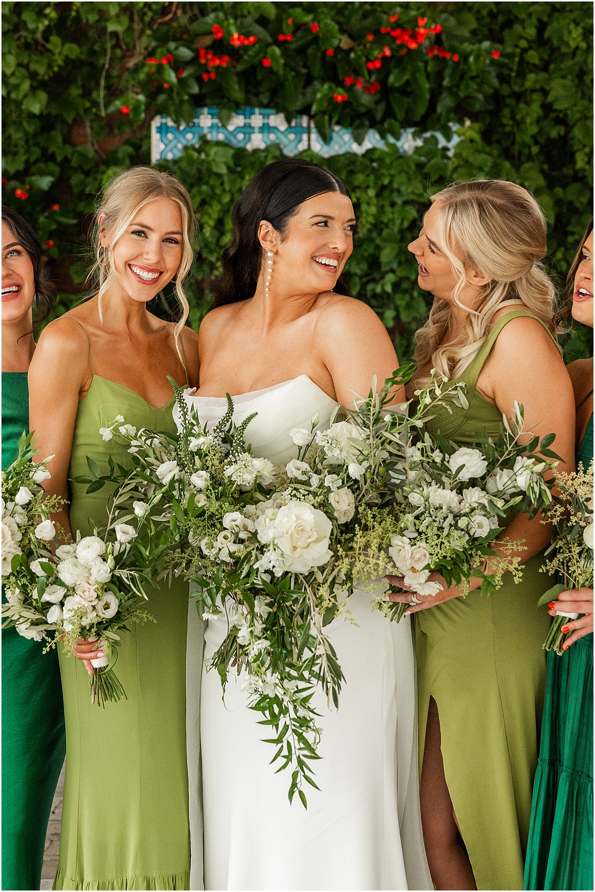 bride with bridesmaids holding cascading bouquets of white flowers and greenery