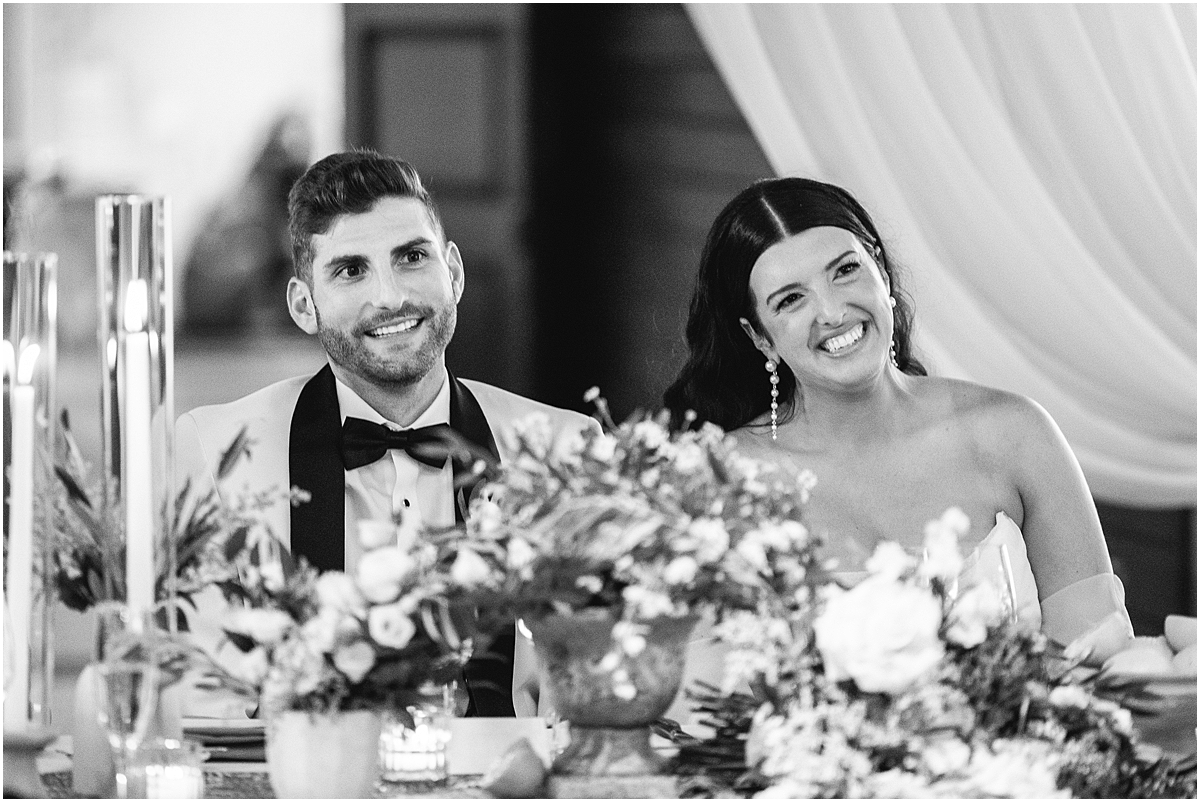 newlyweds sit together at head table during Galleria Marchetti Summer Wedding in Chicago