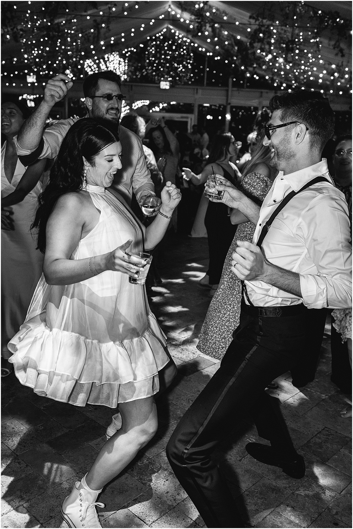 bride and groom dance together with guests surrounding them