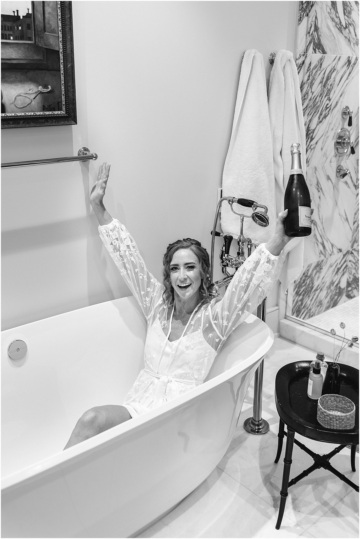 bride in bathtub holding bottle of champagne
