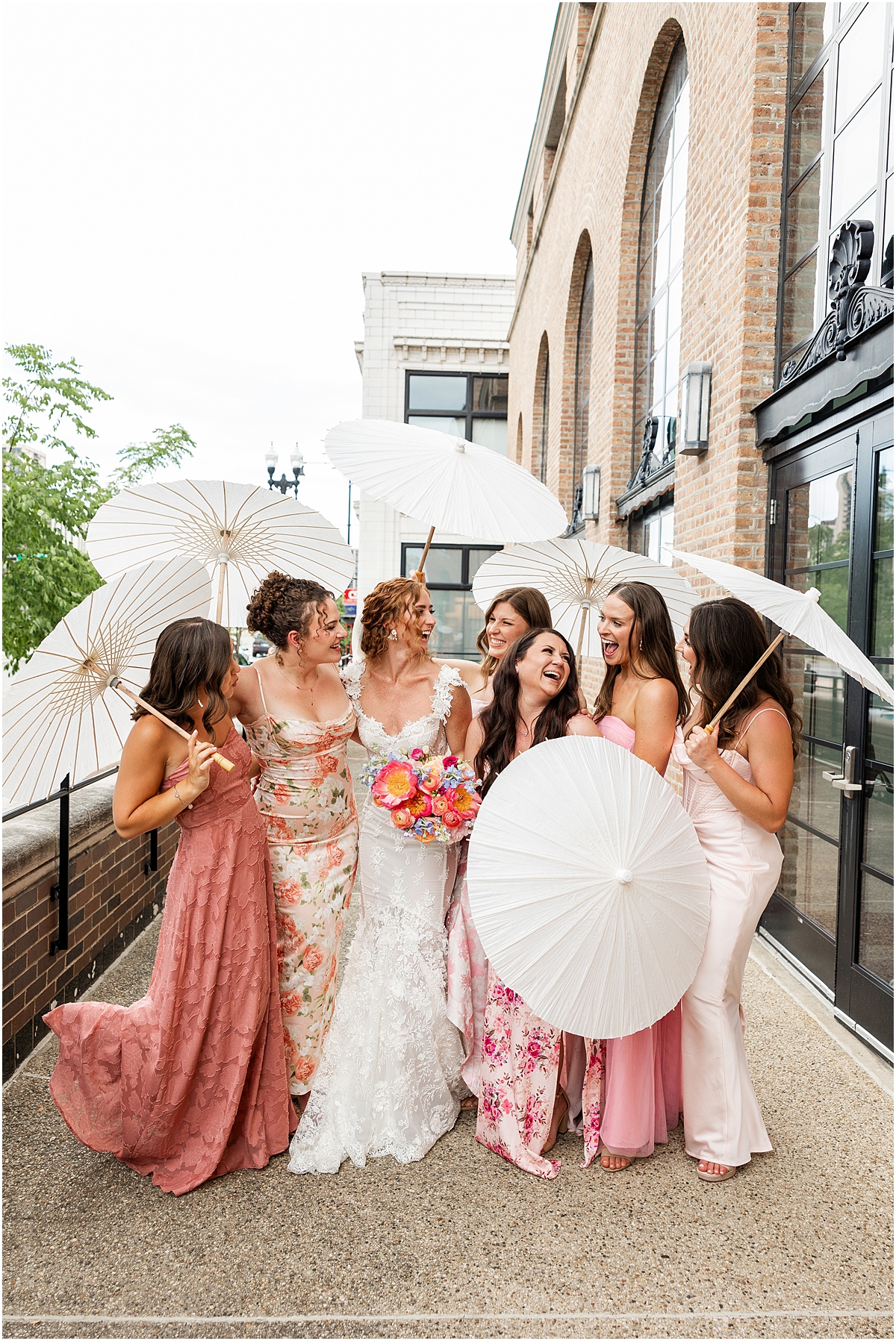 bride and bridesmaids holding stylish white umbrellas after Summer Wedding at Revel Motor Row