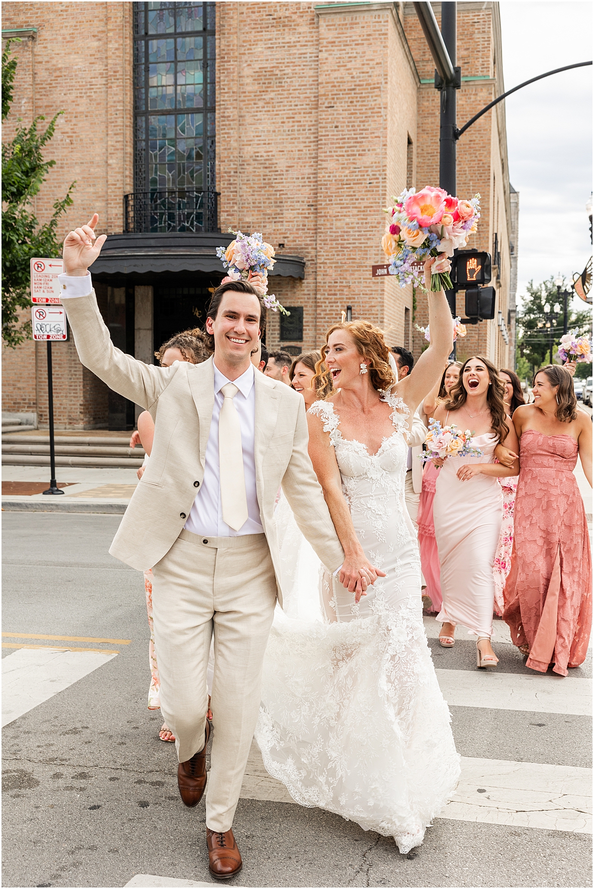 newlyweds cross street with wedding party behind them in Chicago
