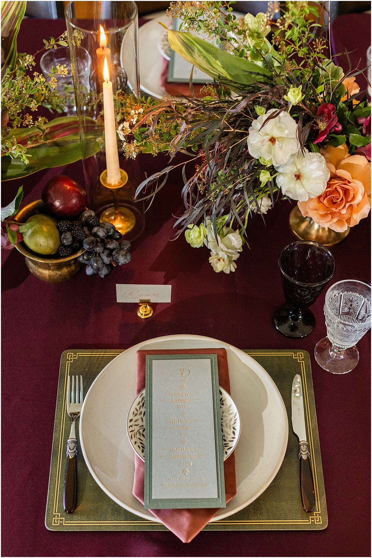 layered place setting with pink napkin, patterned plate and dark green bordered menu