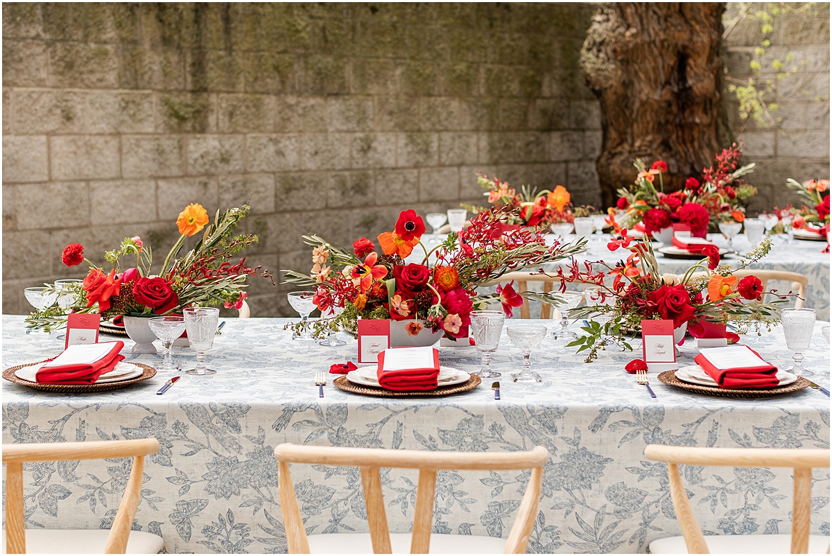 red flower centerpieces on blue patterned linens