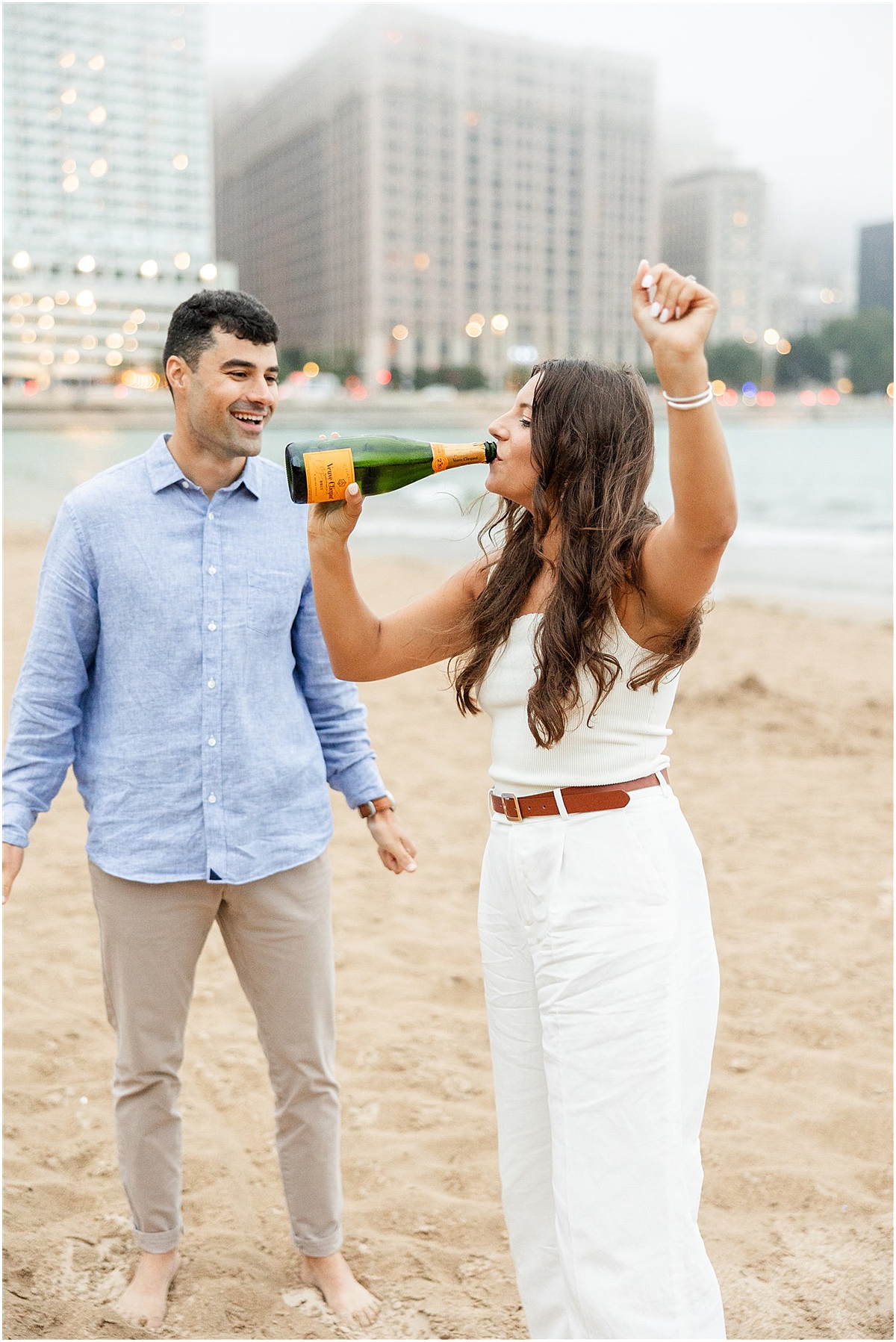 couple celebrate engagement session with bottle of champagne at North Avenue Beach