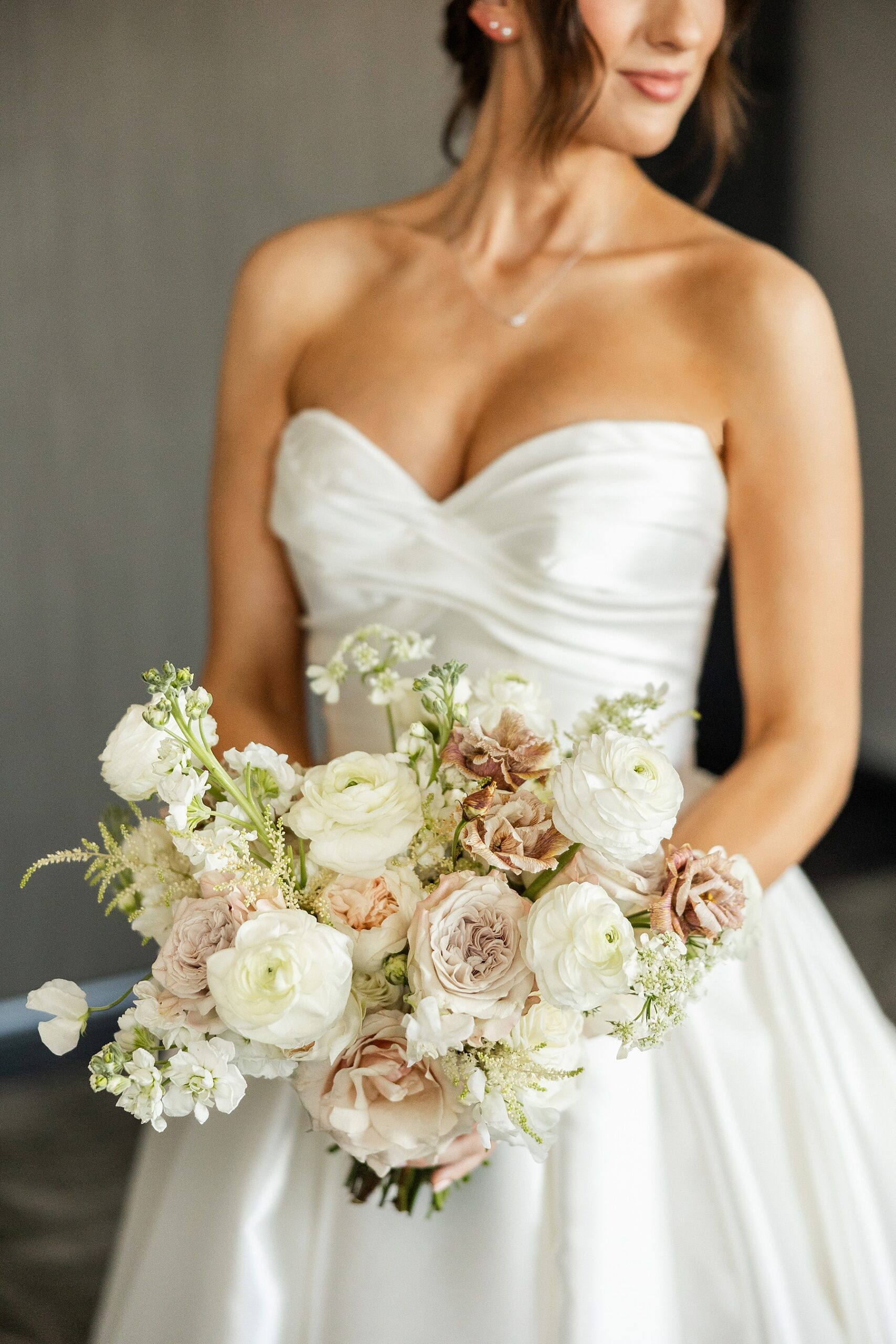 elegant bride in strapless wedding dress and holding soft florals