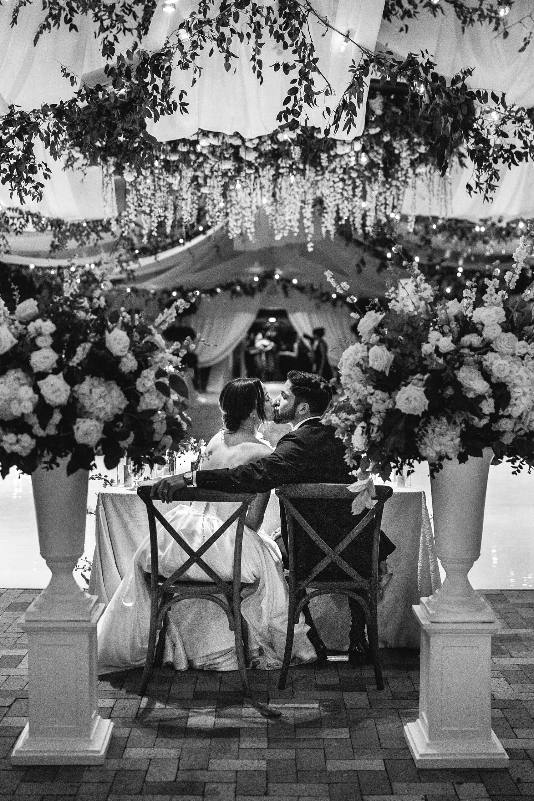 newlyweds kiss as they sit together at sweetheart table 
