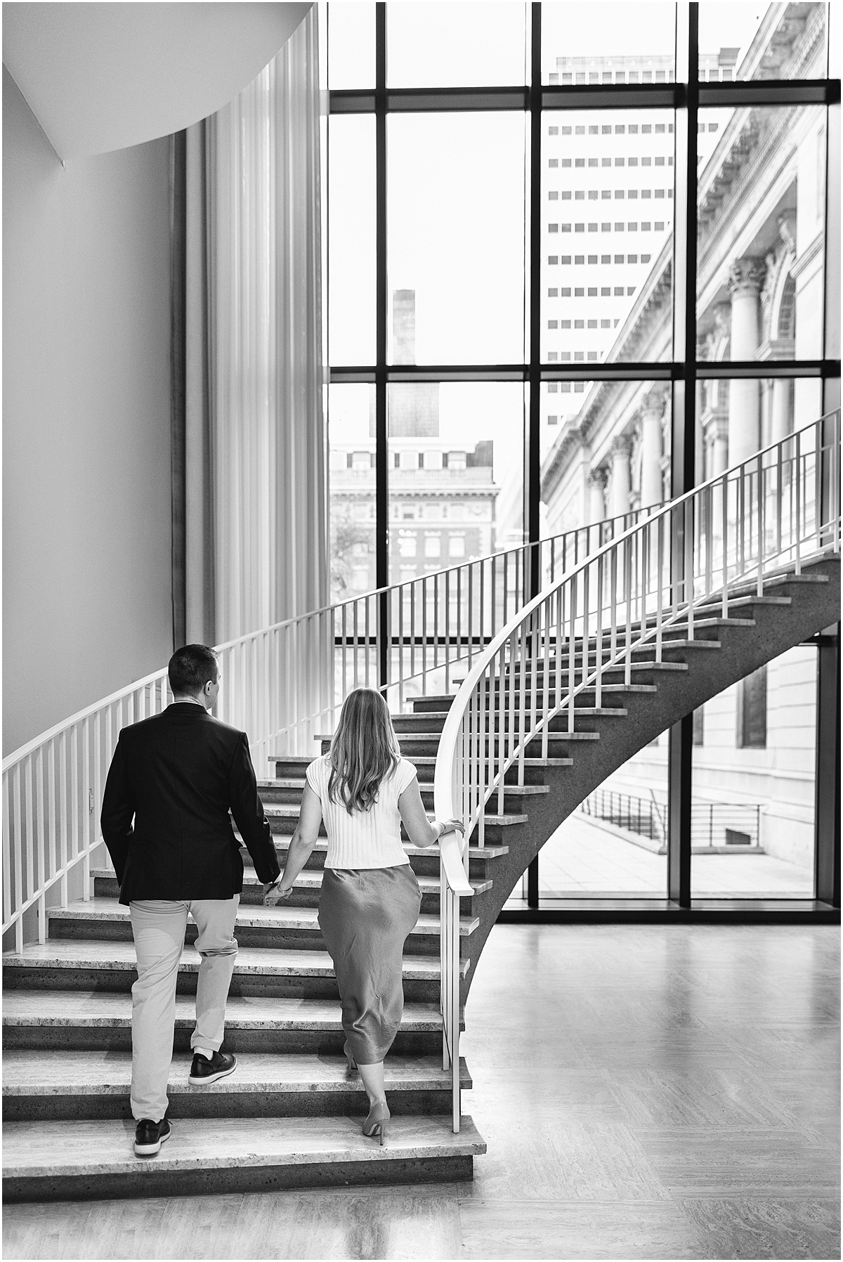 couple walk up spiral staircase in museum 