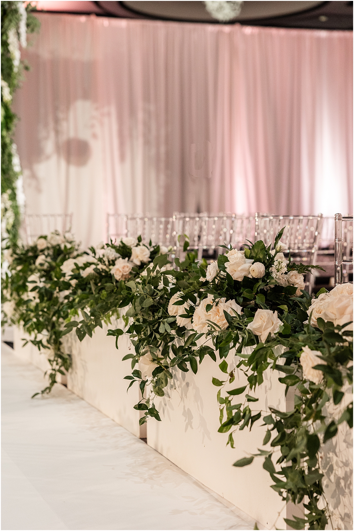 white roses and greenery decorate wedding ceremony 