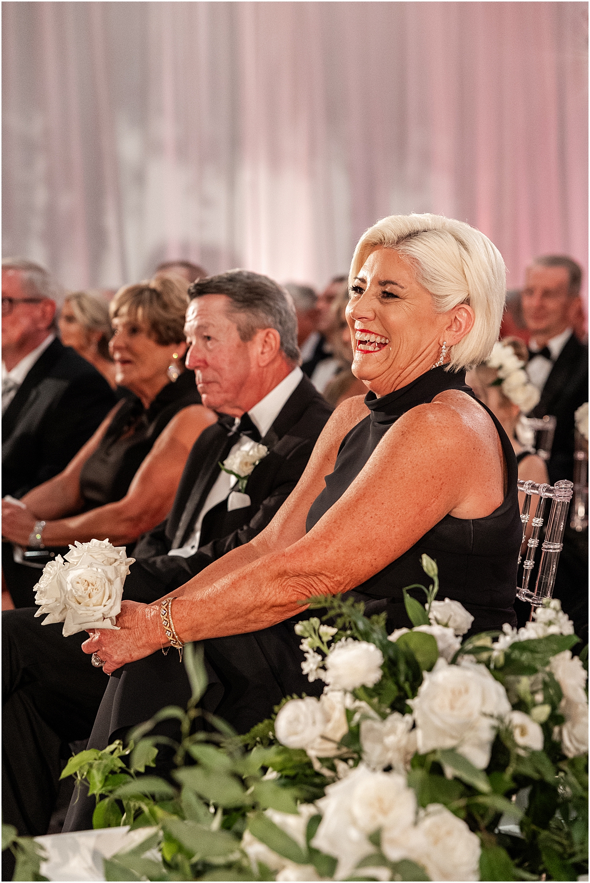 guests smile and laugh as they watch wedding ceremony 
