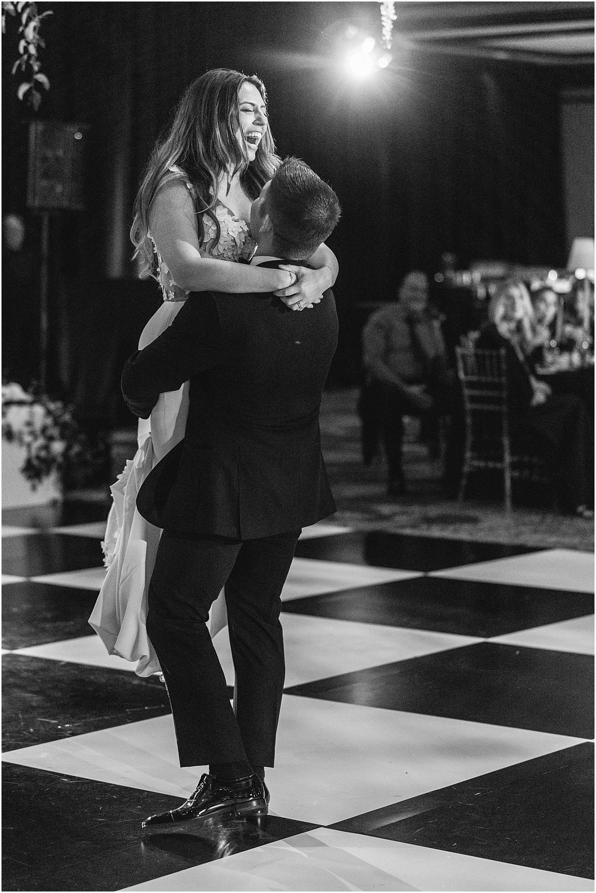 groom lifts his wife up on the dance floor 