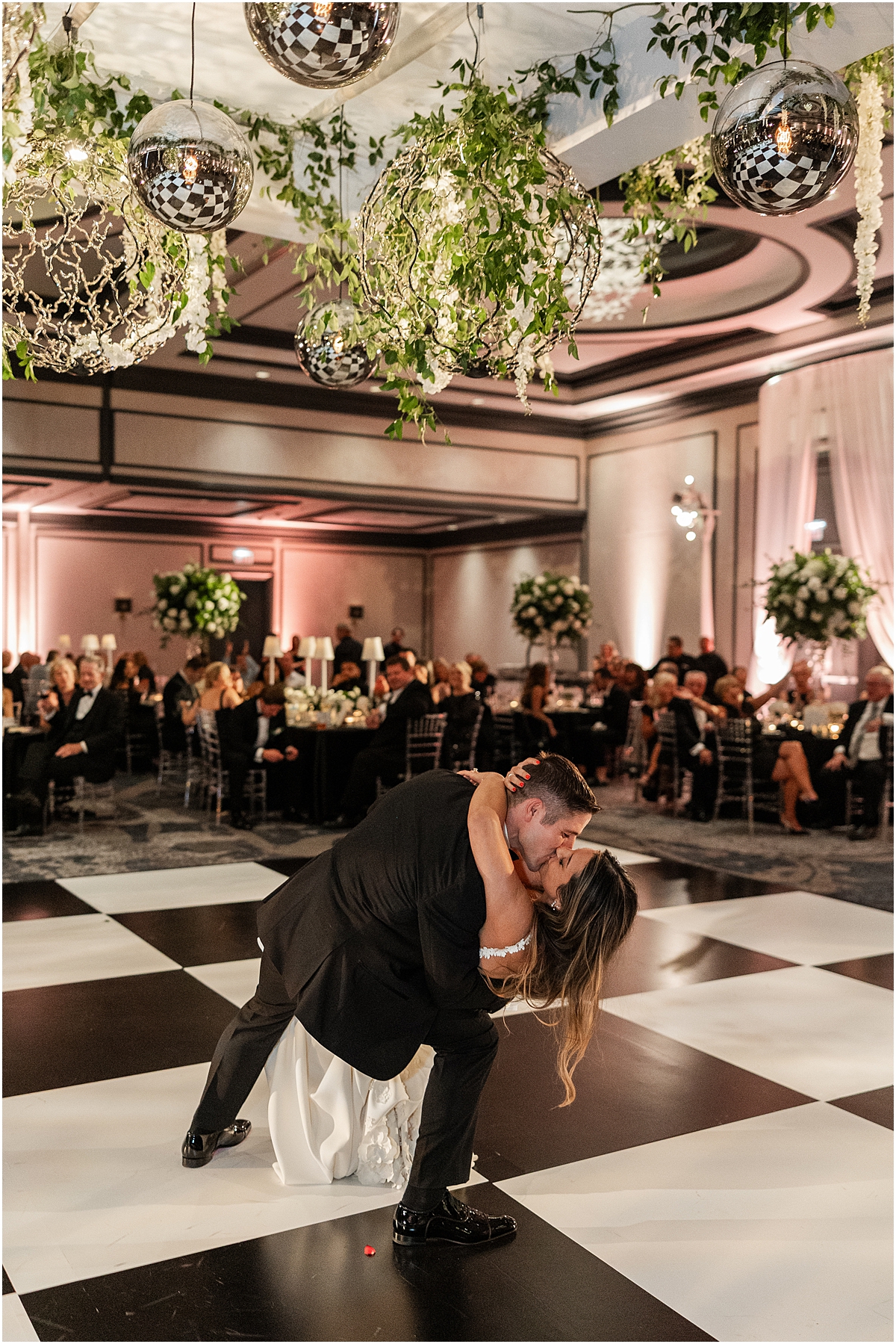 groom dips his bride on the dance floor as they kiss